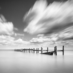 Square format black and white long exposure of the old sea defence groynes at Happisburgh beach on the Norfolk coast
