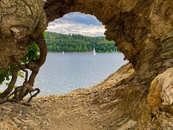 view of a lake framed by a cave with sailboats in summer