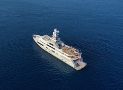 Aerial panoramic top down drone photo of a super yacht anchored in deep blue water in the Mediterranean sea in Greece