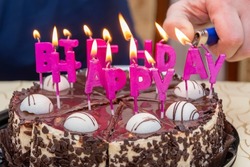 They light a fire on birthday candles on a cake, a festive table in an apartment,selective focus.