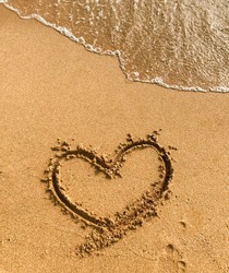 Drawing heart shape love concept on sand at the beach with vacation holiday summer travel background.