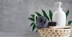 Gray towel, body massage brush, black bristle brush, foot penza, green ailanthus branch on gray background, bath accessories concept, bath products