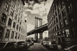 Manhattan bridge seen from a brick buildings in Brooklyn street in perspective, New York, USA. Business and travel background. Vintage, retro postcard with sepia filter.