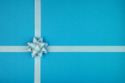 Blue bow and ribbon crossed to decorate gifts, greetings, holidays on a blue background. Background for a postcard.