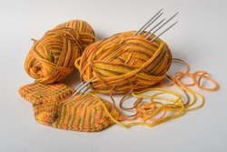 Orange yarn with sock and spokes on white background