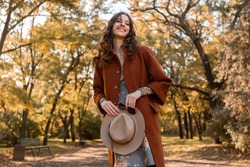 close-up hands details of attractive stylish woman holding hat and sunglasses walking in park dressed in warm coat autumn trendy street fashion style accessories