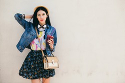 young beautiful happy stylish hipster girl, cocktail, smoozy drink, denim jacket, smiling, fashion, teen, cool accessories, purse, hat, sunglasses, amazed, vintage style outfit, wall background