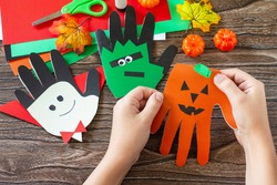 In the hands of a child Greeting card halloween on wooden table. Children's creativity project, crafts, crafts for kids.