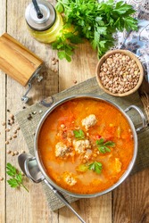 Tomato lentil soup with meatballs and vegetables on a wooden table.  Top view flat lay background.