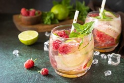 Soft drinks, healthy beverage, slimming water. Refreshing detox drinks made from organic raspberries, cucumbers, lime and mint leaves on a stone table.