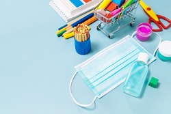 School supplies, poppit anti-stress, face mask, bottle of sanitizer, for back to school on a blue background. Covid-19 precautions, staying healthy. Copy space.
