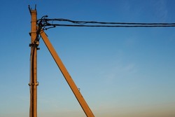 Photo of a pillar with wires on the street against the background of a clear blue sky.