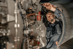 Male worker maintenance technician using wrench while repairing aircraft at repair station