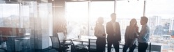 Business team standing against panoramic windows in modern office. Blurred background