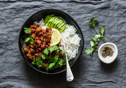 Rice bowl with spicy beans minced meat stew with cilantro and avocado on grey background, top view              