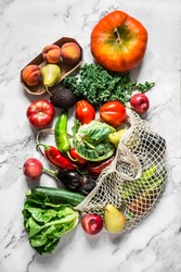 Seasonal vegetables on a marble background - kale cabbage, zucchini, eggplant, pepper, cauliflower, tomatoes, pumpkin and pears, apples, peaches. Top view        