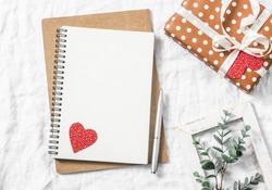 Valentine's day background. Empty blank notebook, gift box, flowers on a white background, top view. Free space for text 