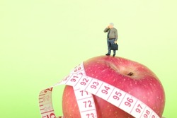 Obese business man miniature figure standing on red apple making phone call