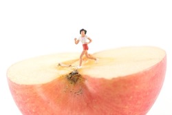 Miniature doll model running and exercising on half of an apple
