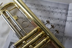 Gold trumpet laying on musical sheet