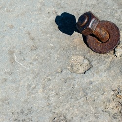 Rusty Screw in a rock with hard shadow