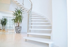 Modern design indoor staircase with white steps and metal railing.