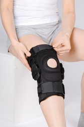 Knee Support Brace on leg isolated on white background. Elastic orthopedic orthosis. Anatomic braces for knee fixation, injuries and pain. Protective knee joint bandage sleeve. Trauma, rehabilitation.