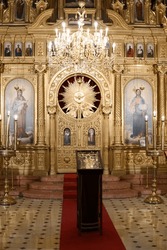 Golden altar and interior of the holy church with paintings of Maria, Joseph and Jesus - light from a golden chandelier