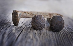 Three rusty old railroad nails on a wood background