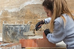 Woman learning for the first time to make a brick wall to make her diy house