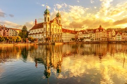 Amazing colorful sunset city center of Lucerne of Lake Lucerne in Central Switzerland. Jesuitenkirche or Jesuit Church of St. Francis Xavier reflects on Reuss river. Famous landmark of historical city