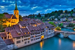 Skyline of Bern, capital of Switzerland at blue hour reflecting in Aare river. Panoramic view of old city, Nydegg Church and Untertorbrucke bridge. Landmark of historical town UNESCO World Heritage.
