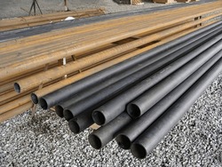 Storage of long plastic and steel pipes on the construction site, crushed stone floor. Building materials and structures.