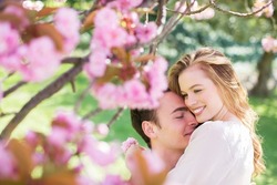 Couple hugging under tree with pink blossoms