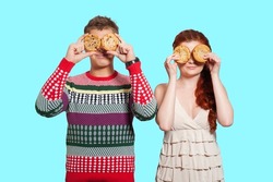 Portrait of a man and a girl closing their eyes with delicious cookies on a blue pastel isolated background. Cute attractive funny funny positive crazy. Close-up
