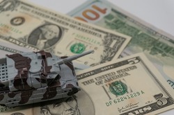 Tanks are placed on top of dollar bills. A metaphor for currency warfare, financial crises, trade wars, tariff penalties, international competition, war costs, and military spending.