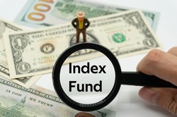 Index Fund.Magnifying glass showing the words.Background of banknotes and coins.basic concepts of finance.Business theme.Financial terms.