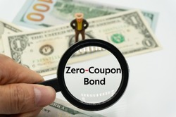 Zero-Coupon Bond.Magnifying glass showing the words.Background of banknotes and coins.basic concepts of finance.Business theme.Financial terms.