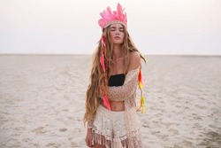 Beautiful boho styled girl with long hair on the sunset beach