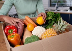 An anonymous young woman checks her fruit and veg delivery box