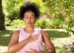Young mutli-ethnic woman practices deep belly breathing, meditation in park