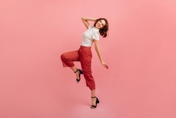 Inspired slim girl dancing on pink background. Studio shot of graceful trendy woman in black shoes.