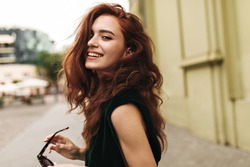 Attractive woman in dark green outfit smiling outside