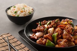 chicken chilli chinese with fried rice served in dish isolated on dark background side view