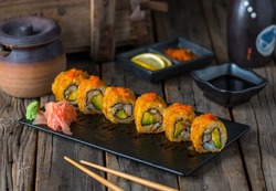 CRUNCHY CALIFORNIA sushi roll served in a cutting board isolated on wooden background side view of sushi roll