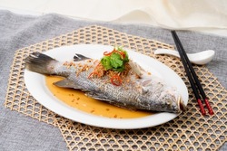 STEAMED SEA BASS IN HK STYLE with chopsticks served in dish isolated on table top view of singapore food