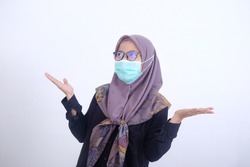 portrait of a Muslim woman in a mask with a confused gesture