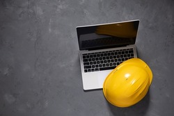 Computer laptop at cement floor. Laptop and construction tool on concrete background