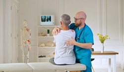 A Doctor Conducts a Physiotherapy Session After a Medical Trauma with a Man in the Modern Rehabilitation Clinic. Rehabilitation Concept