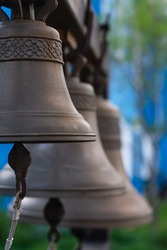 several Church bells, bell ringing on blue blurred background. bells cast according to old recipe from special metal, alloy of copper and zinc. was believed that ringing of bells heals.